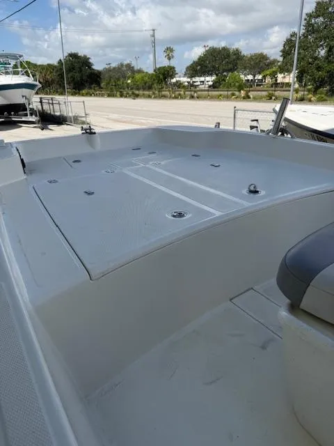 Slide: The Image of 2023 Mako Pro Skiff 17 CC boat deck with storage compartments, parked outdoors. - 11