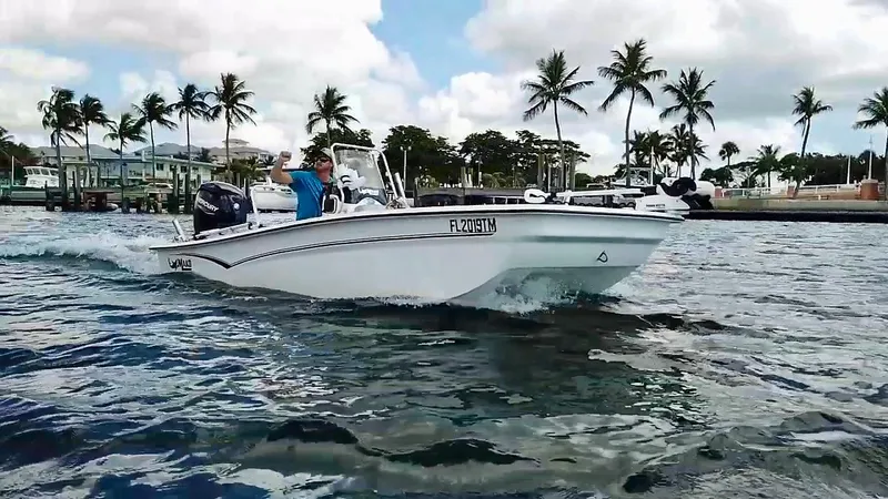 Slide: The Image of 2023 Mako Pro Skiff 17 CC boat cruising on water with palm trees in background. - 5