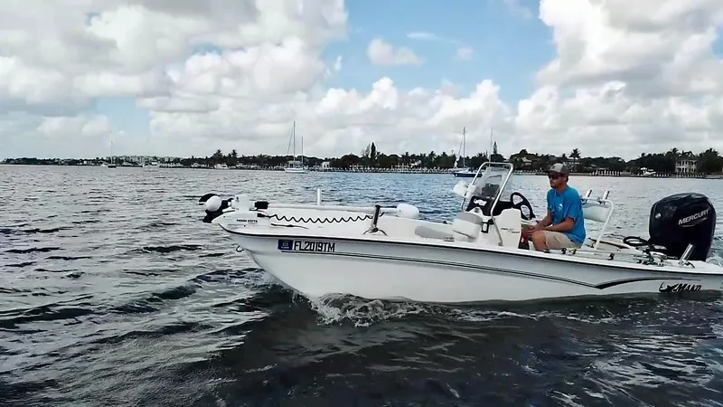 Slide: The Image of 2023 Mako Pro Skiff 17 CC boat cruising on a calm, scenic waterway. - 7