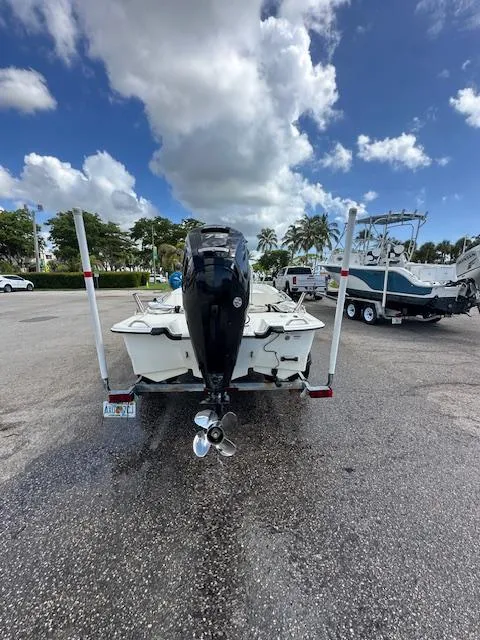 Slide: The Image of 2023 Mako Pro Skiff 17 CC boat on trailer, parked under a partly cloudy sky. - 8