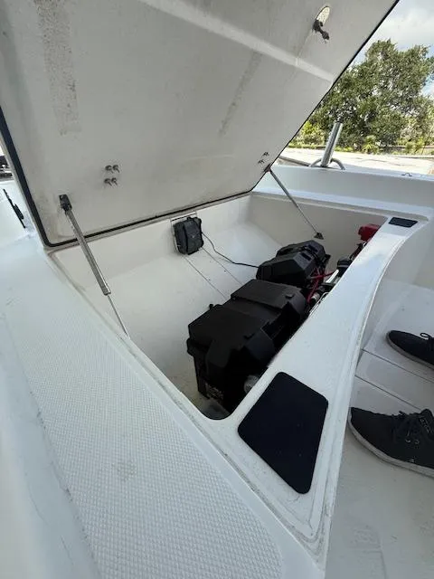 Slide: The Image of Open storage compartment of 2023 Mako Pro Skiff 17 CC boat, showing battery and wiring. - 9