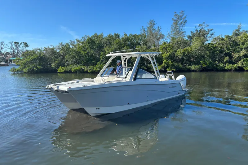 Slide: The Image of 2026 World Cat 265 DC-X boat cruising on a calm river with lush greenery. - 5