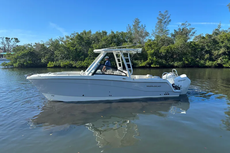 Slide: The Image of 2026 World Cat 265 DC-X boat cruising on calm water near lush greenery. - 6