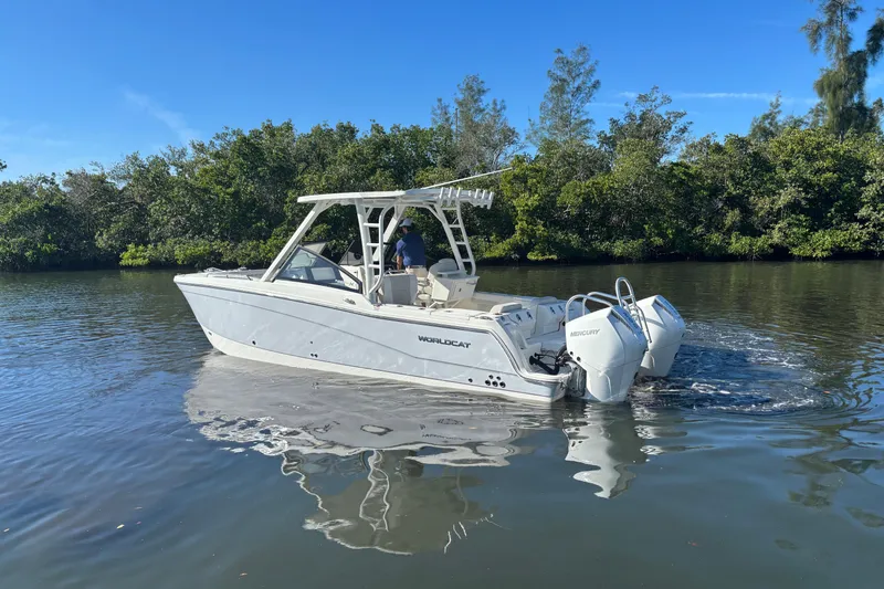 Slide: The Image of 2026 World Cat 265 DC-X boat cruising on a calm river under clear blue skies. - 7