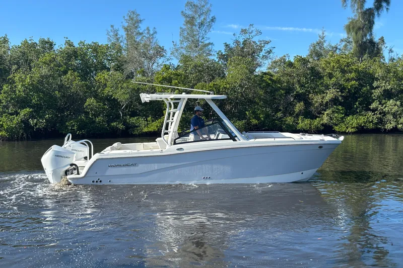 Slide: The Image of 2026 World Cat 265 DC-X boat cruising on a calm river with lush greenery. - 9