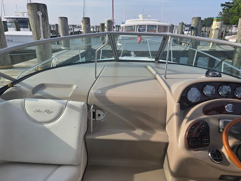 Slide: The Image of 2004 Sea Ray 280 Sundancer helm with gauges, steering wheel, and docked boats in background. - 11