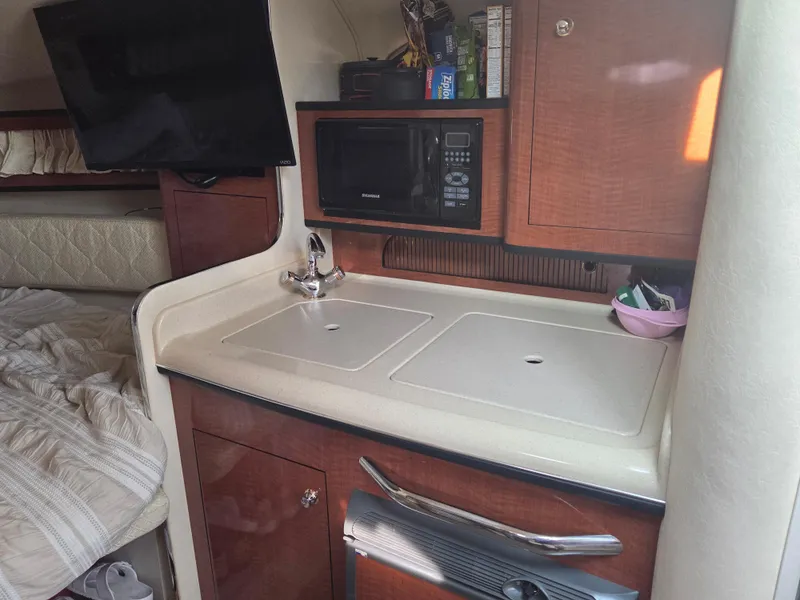 Slide: The Image of 2004 Sea Ray 280 Sundancer interior with kitchenette, sink, and microwave. - 13