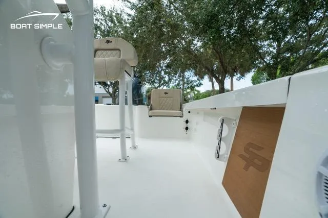 Slide: The Image of 2024 Sea Pro 208 Bay boat interior with seating and storage, surrounded by trees. - 19