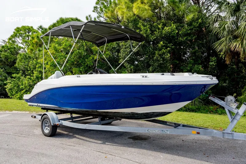 Slide: The Image of 2021 Hurricane SunDeck Sport 205 OB boat on trailer, blue hull, parked outdoors. - 1