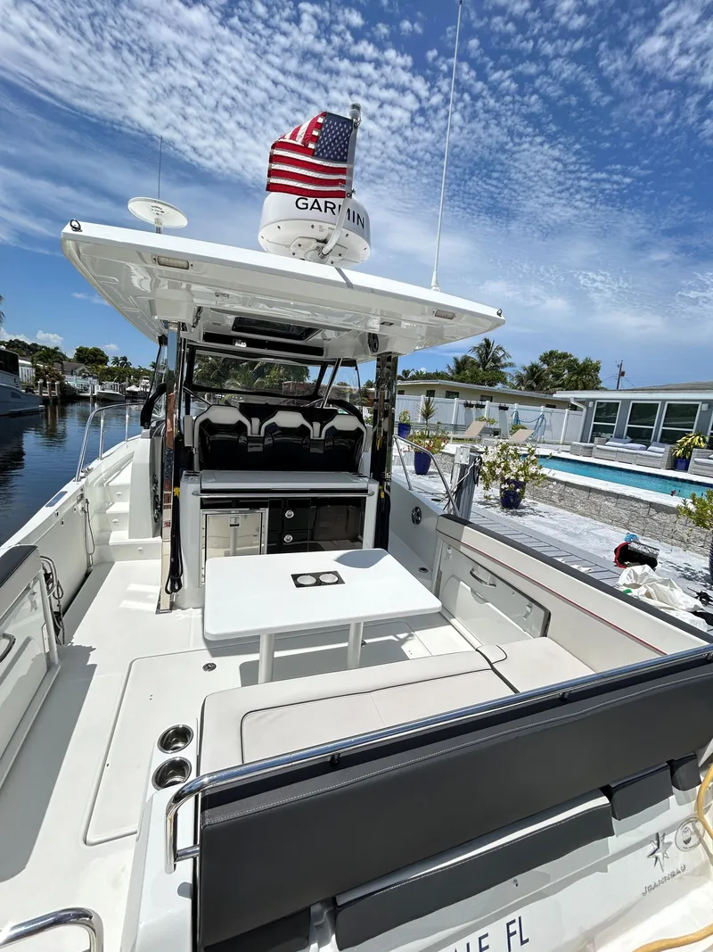 Slide: The Image of 2022 Jeanneau Leader 10.5 WA Series 2 boat with seating and table, docked under blue sky. - 15