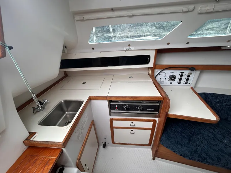 Slide: The Image of 1999 Catalina 270 yacht interior with kitchenette, sink, stove, and control panel. - 15