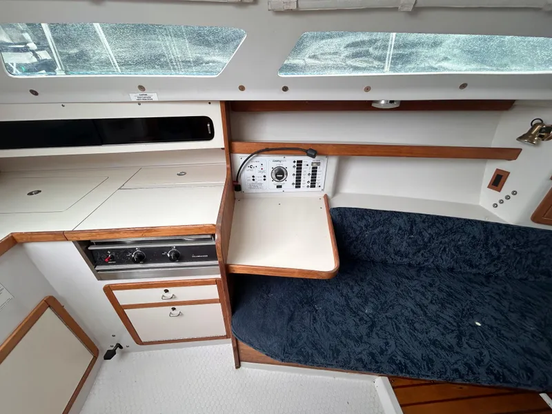 Slide: The Image of Interior of a 1999 Catalina 270 sailboat with a compact kitchen and seating area. - 16