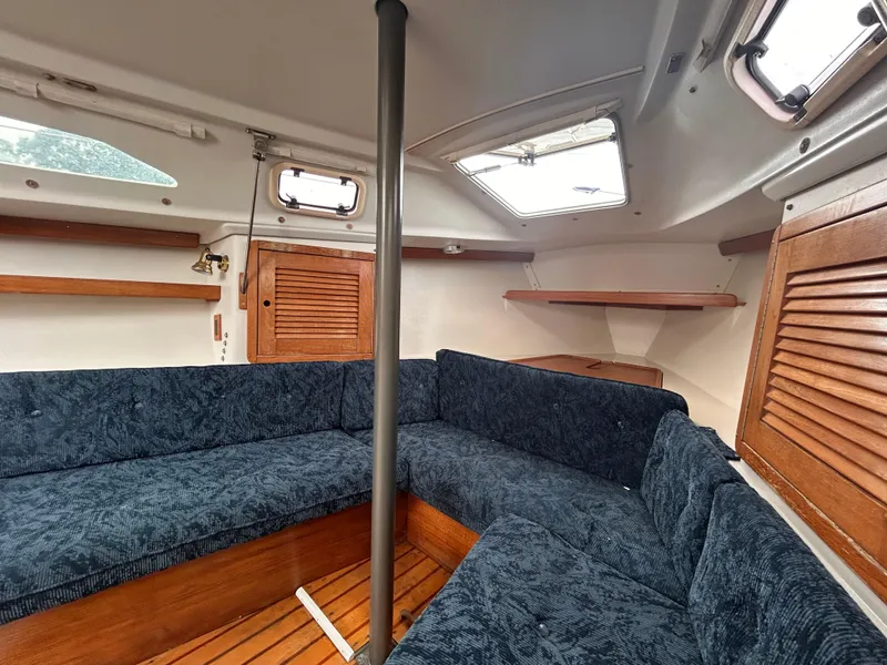 Slide: The Image of Interior of a 1999 Catalina 270 sailboat with blue seating and wooden accents. - 23