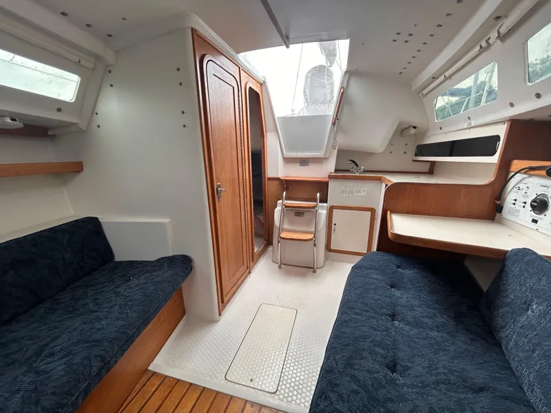 Slide: The Image of Interior of a 1999 Catalina 270 sailboat with seating, wood accents, and navigation area. - 25