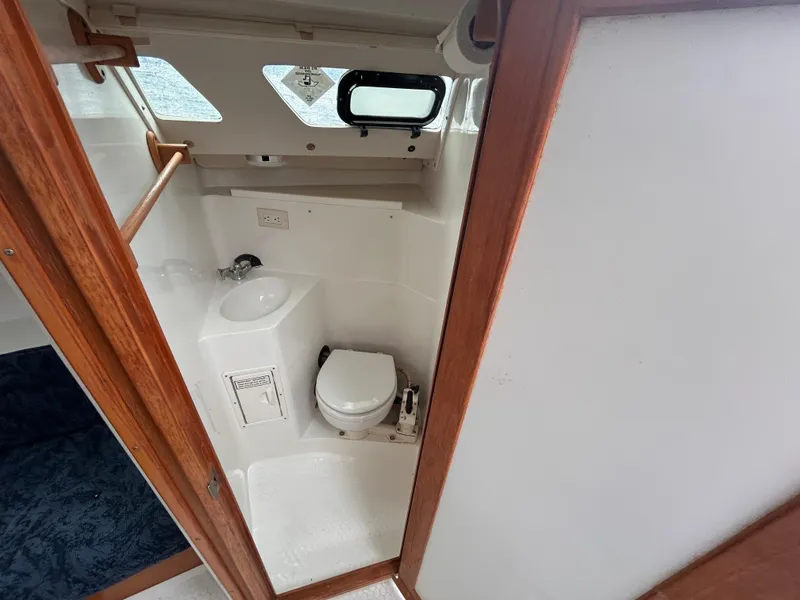 Slide: The Image of 1999 Catalina 270 sailboat bathroom with toilet, sink, and wooden trim. - 26