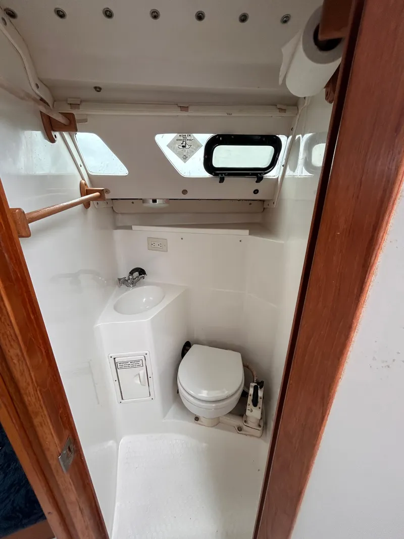 Slide: The Image of Compact bathroom in a 1999 Catalina 270 sailboat, featuring a toilet and sink. - 27