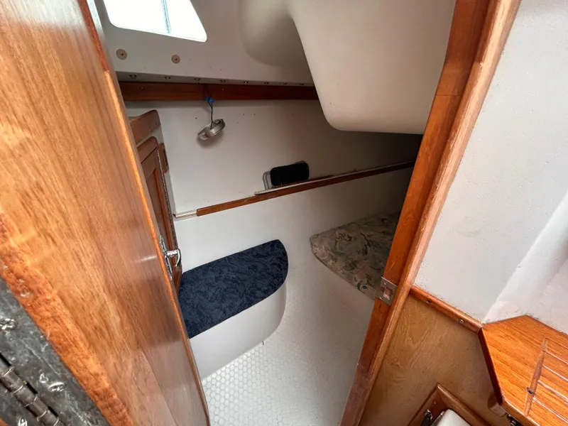 Slide: The Image of Interior cabin of a 1999 Catalina 270 sailboat, featuring wood finishes and compact sleeping area. - 28