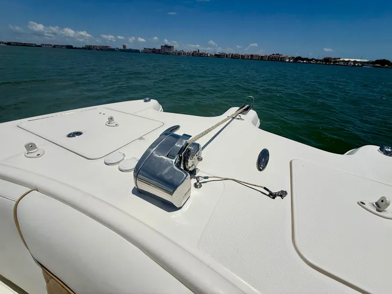 Slide: The Image of 2014 World Cat 295 CC boat deck with anchor, on calm water under clear sky. - 11
