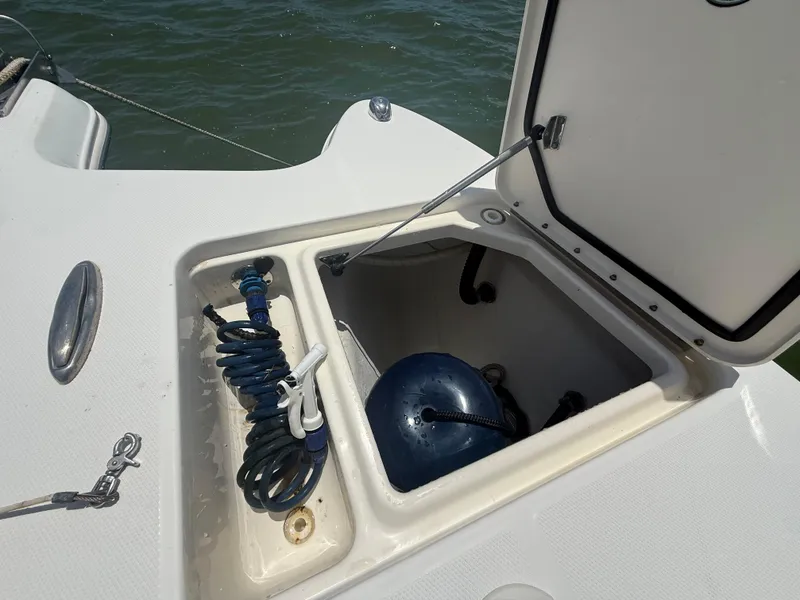 Slide: The Image of Open storage compartment on 2014 World Cat 295 CC boat, featuring coiled hose and fender. - 24