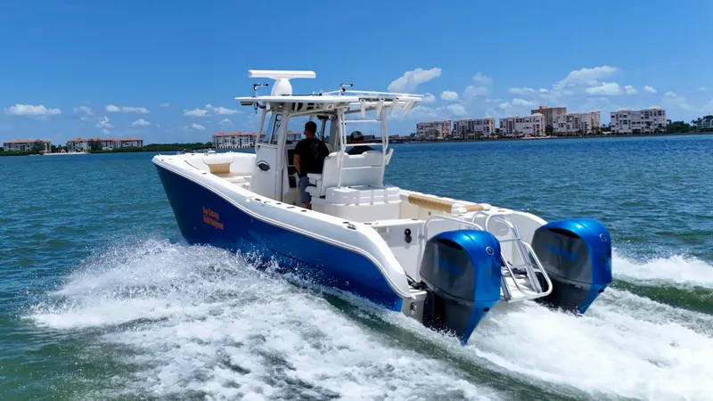 Slide: The Image of 2014 World Cat 295 CC boat cruising on a sunny day with cityscape in background. - 3