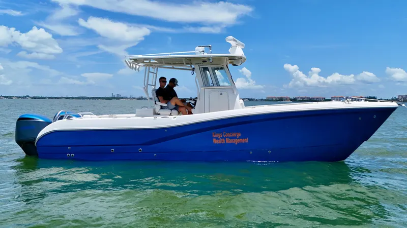 Slide: The Image of 2014 World Cat 295 CC boat on water, blue hull, clear sky background. - 4