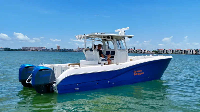Slide: The Image of 2014 World Cat 295 CC boat on water, blue hull, twin engines, clear sky background. - 5