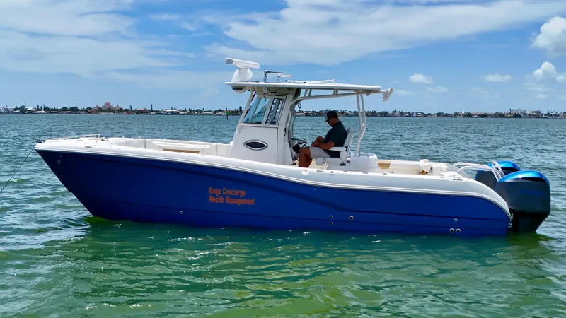 Slide: The Image of 2014 World Cat 295 CC boat on water, blue hull, clear sky background. - 7