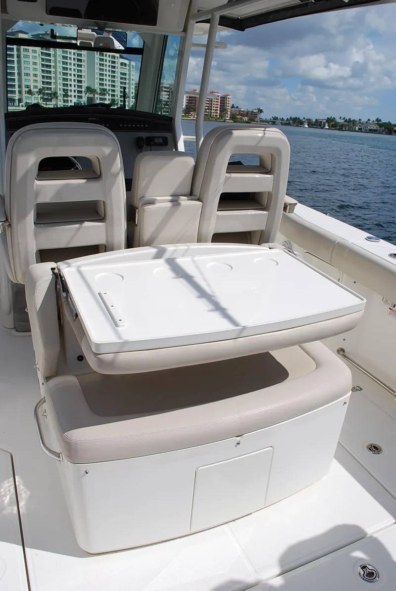 Slide: The Image of 2017 Boston Whaler 330 Outrage interior with seating and table, docked by waterfront buildings. - 12
