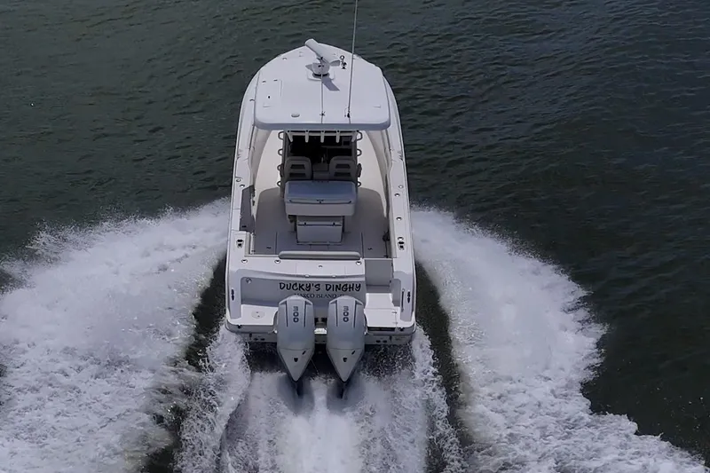 Slide: The Image of 2020 Boston Whaler 330 Outrage cruising on water, rear view with twin engines. - 17