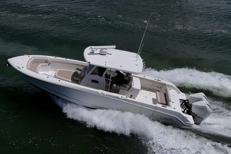 Slide: The Image of 2020 Boston Whaler 330 Outrage cruising on water, showcasing sleek design and powerful engines. - 19