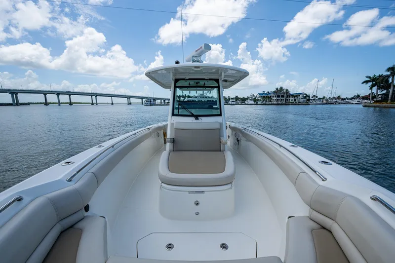 Slide: The Image of 2020 Boston Whaler 330 Outrage boat on calm water, with bridge and marina in background. - 20