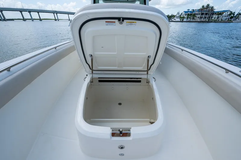 Slide: The Image of 2020 Boston Whaler 330 Outrage storage compartment open on deck, with scenic waterfront view. - 26
