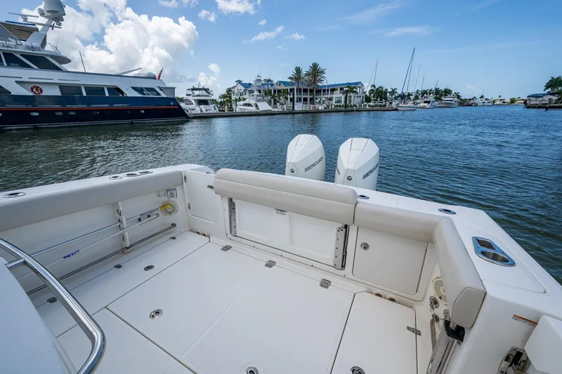 Slide: The Image of 2020 Boston Whaler 330 Outrage boat docked, featuring spacious deck and twin Mercury engines. - 36