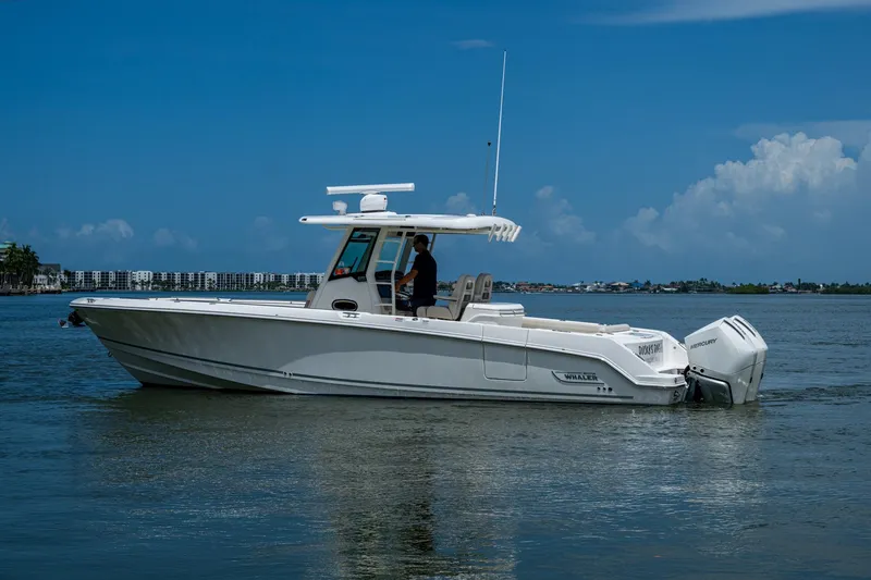 Slide: The Image of 2020 Boston Whaler 330 Outrage boat cruising on calm waters under a clear blue sky. - 6