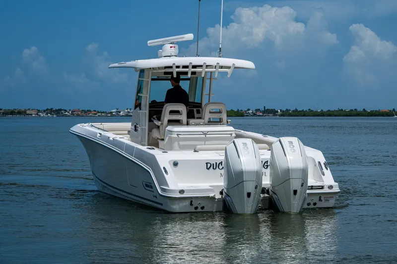Slide: The Image of 2020 Boston Whaler 330 Outrage boat on calm water, rear view with dual engines. - 7