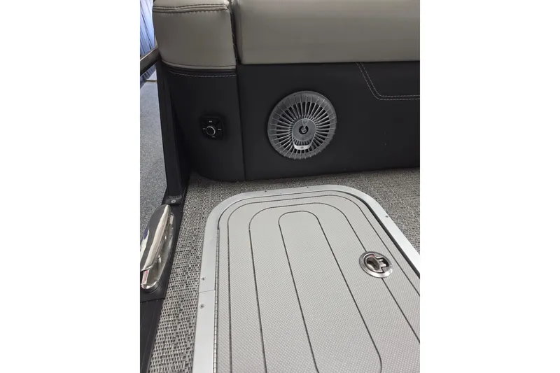 Slide: The Image of 2026 Barletta Lusso 25UC boat interior, featuring a speaker and storage compartment on carpeted flooring. - 19