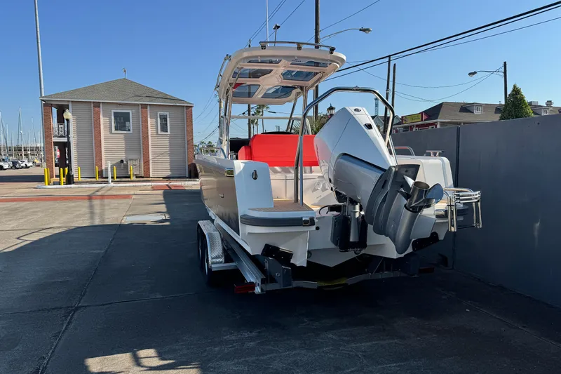Slide: The Image of 2025 Nimbus Tender 8 boat on trailer, parked near marina building under clear blue sky. - 14