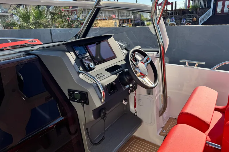 Slide: The Image of Interior of 2025 Nimbus Tender 8 boat with modern dashboard and red seating. - 23