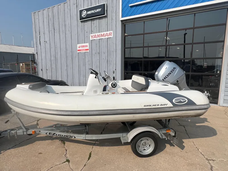The Image of 2017 Walker Bay Generation 360 DLX inflatable boat on trailer, parked outside a dealership. - 1