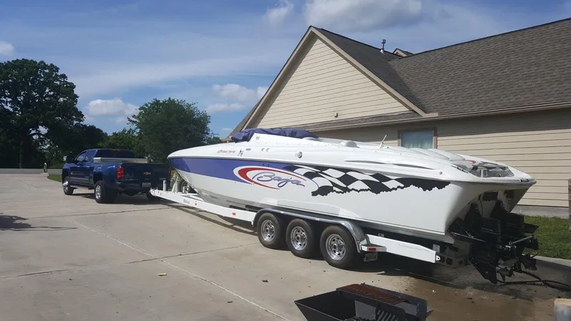 The Image of 2001 Baja 342 boat on trailer, parked beside a house, with a blue truck. - 1