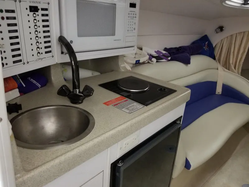 Slide: The Image of 2001 Baja 342 boat interior with kitchenette, featuring sink, stove, microwave, and seating area. - 5