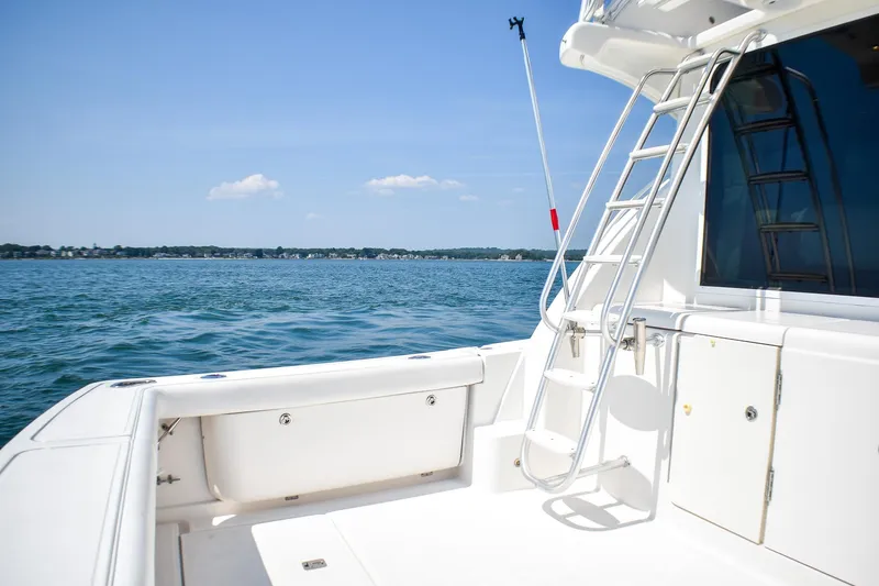 Slide: The Image of 2006 Tiara Yachts 3900 Convertible on calm waters, featuring a sleek deck and ladder. - 25