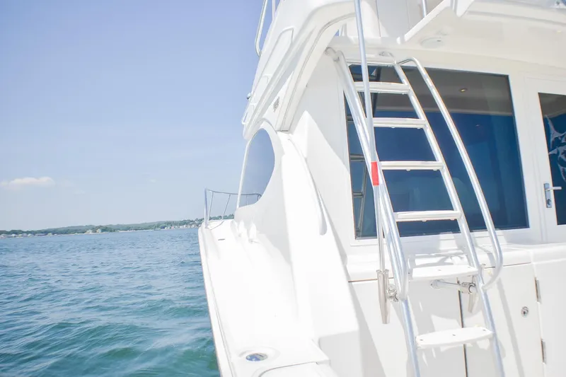 Slide: The Image of 2006 Tiara Yachts 3900 Convertible on calm water, featuring sleek design and ladder. - 28