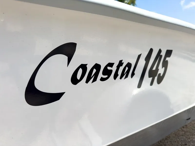 Slide: The Image of 2026 Coastal Skiff 145 boat logo on white hull, close-up view. - 13