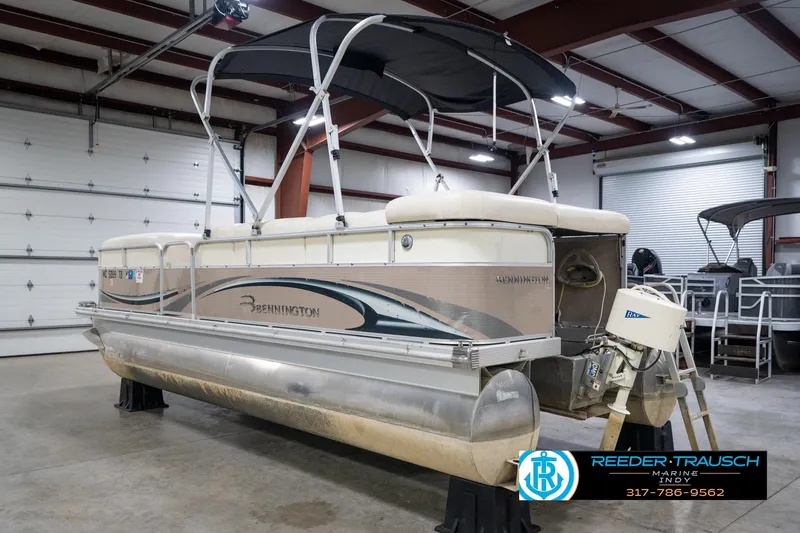Slide: The Image of 2008 Bennington 20 SL pontoon boat in indoor storage, featuring a canopy and outboard motor. - 10