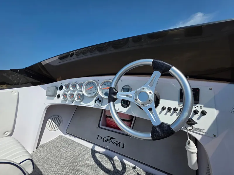 Slide: The Image of 2018 Donzi 22 Classic boat dashboard with steering wheel and gauges under clear blue sky. - 11