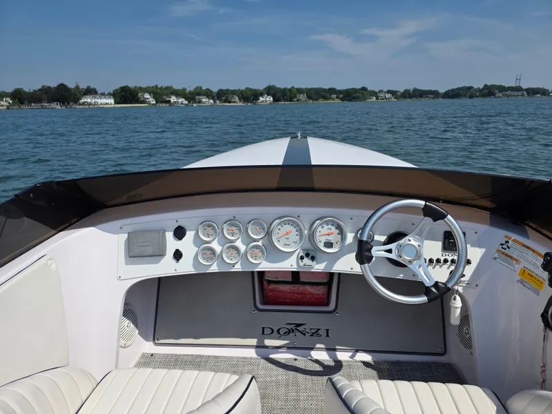 Slide: The Image of 2018 Donzi 22 Classic boat dashboard with gauges and steering wheel on open water. - 12