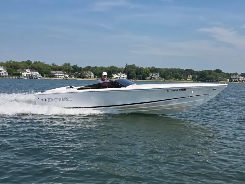 Slide: The Image of 2018 Donzi 22 Classic speedboat cruising on a lake with houses in the background. - 15
