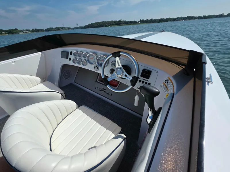 Slide: The Image of 2018 Donzi 22 Classic boat interior with white seating and steering wheel on a lake. - 8