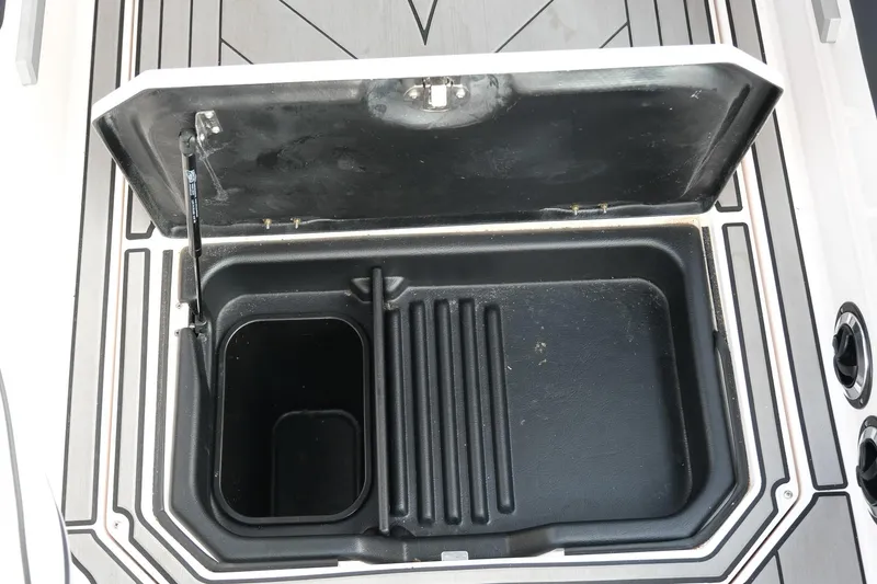 Slide: The Image of Open storage compartment in a 2020 Supra SL450 boat, featuring a black interior. - 16